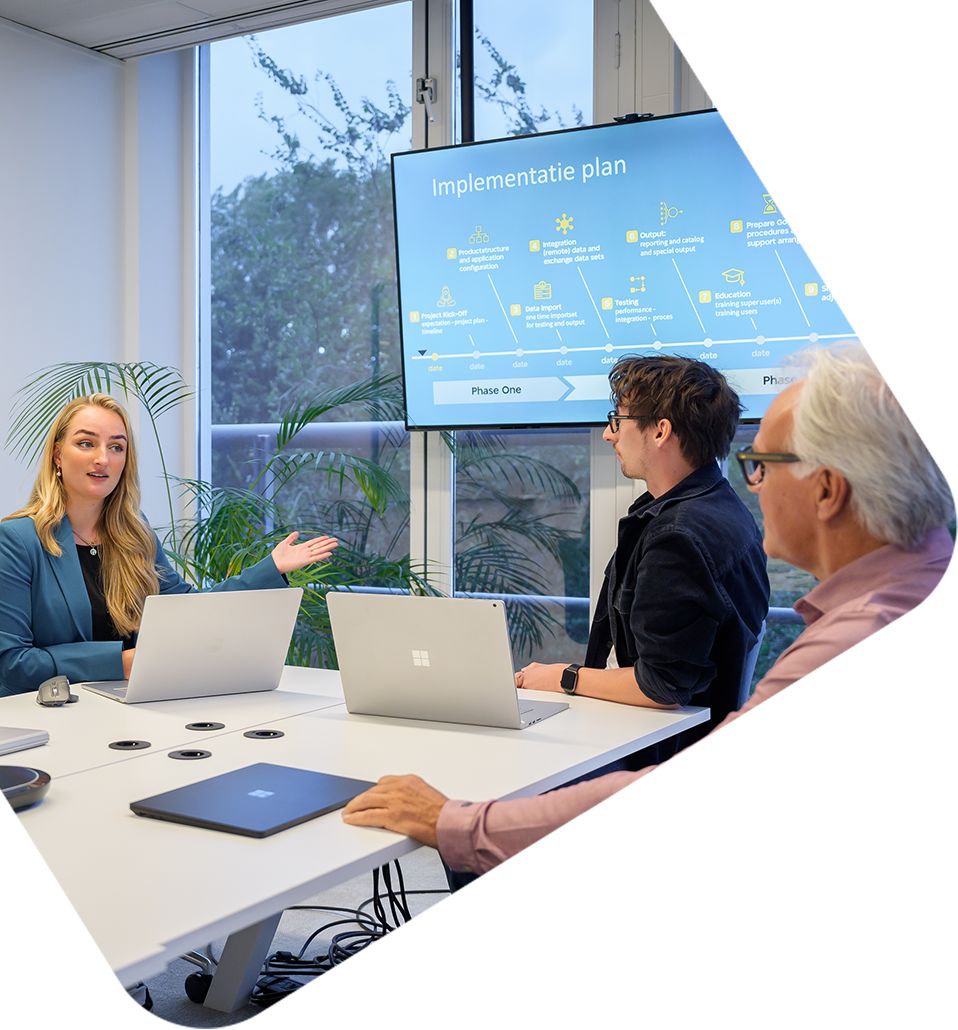 Team in overleg over PIM‑implementatieplan, met planning op scherm en laptops in moderne vergaderruimte